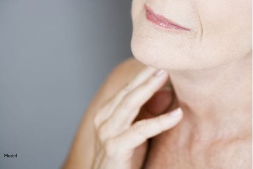 A senior woman touching her neck
