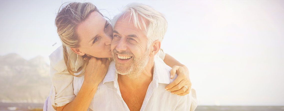 Two older male and female models romantically embracing