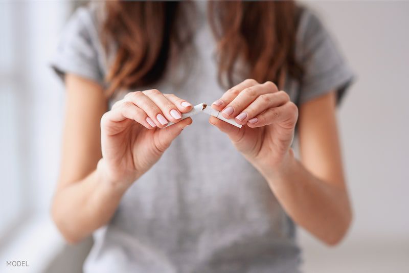 woman breaking a cigarette rather than smoking it.