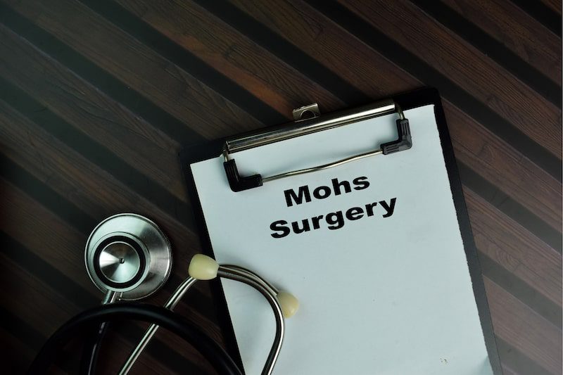 Stethoscope next to a clip board reading 'Mohs Surgery' on desk