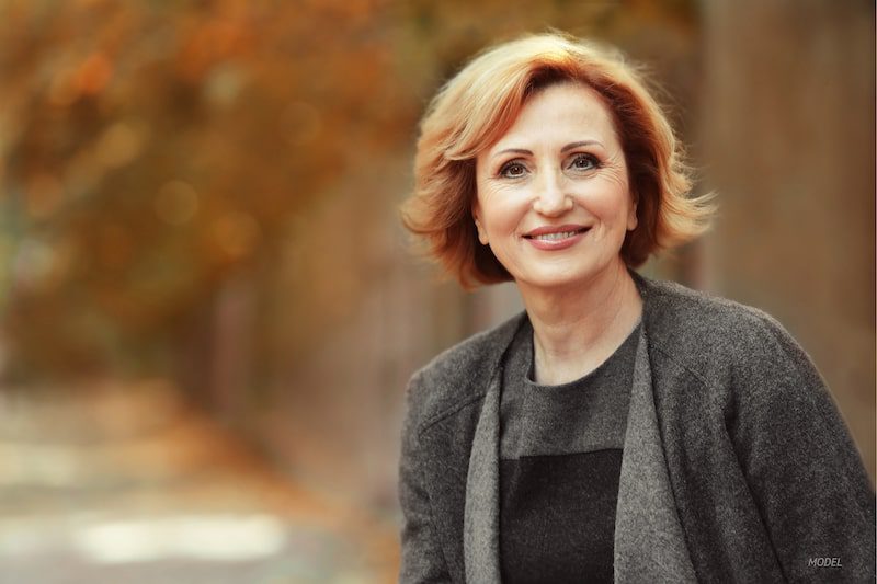 Middle-aged woman standing outside with fall leaves