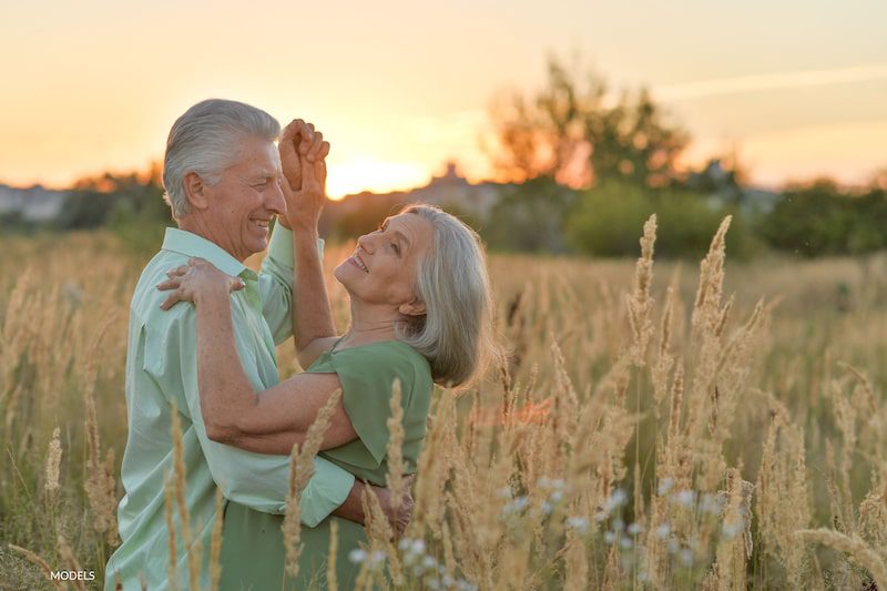 Attractive older couple dancing in a field of wheat.