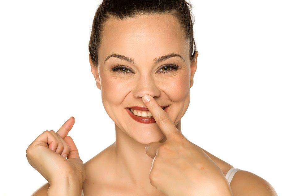 Beautiful, young woman smiling as she touches her nose with her finger