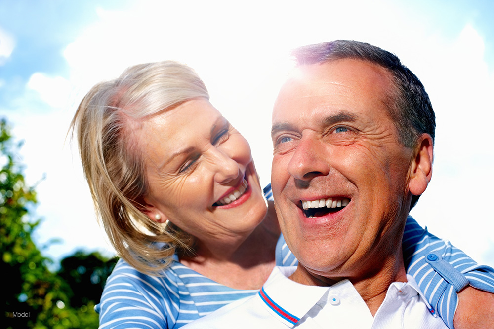 a mature couple smiling outdoors in the sun
